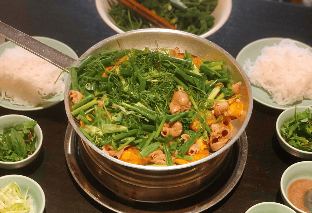 Cha Ca La Vong serves up Hanoi’s iconic turmeric fish dish in a sizzling, herb-filled skillet (Source: Canva)